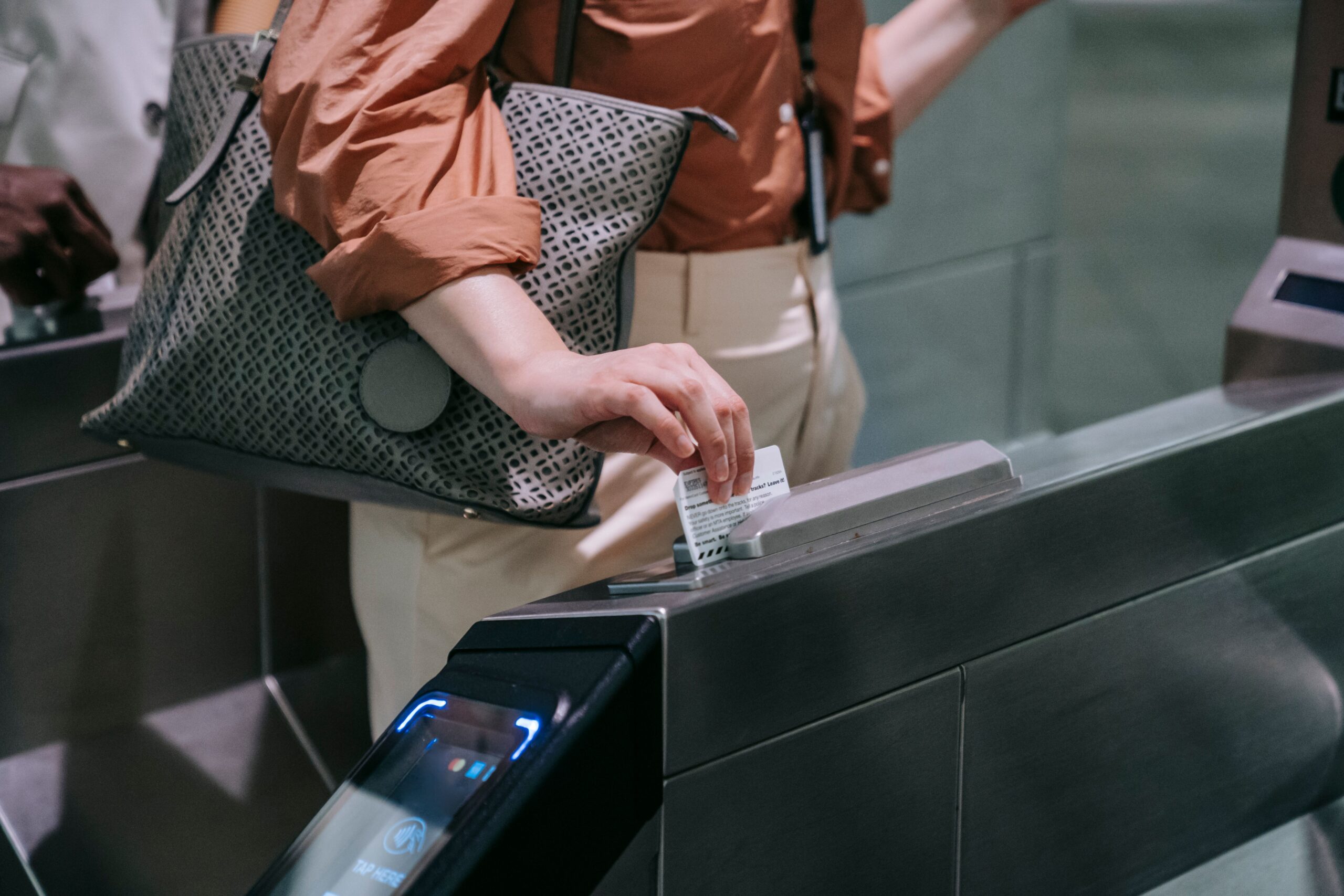 Close-up of woman using ticket at subway entrance turnstile, showcasing modern public transport system.